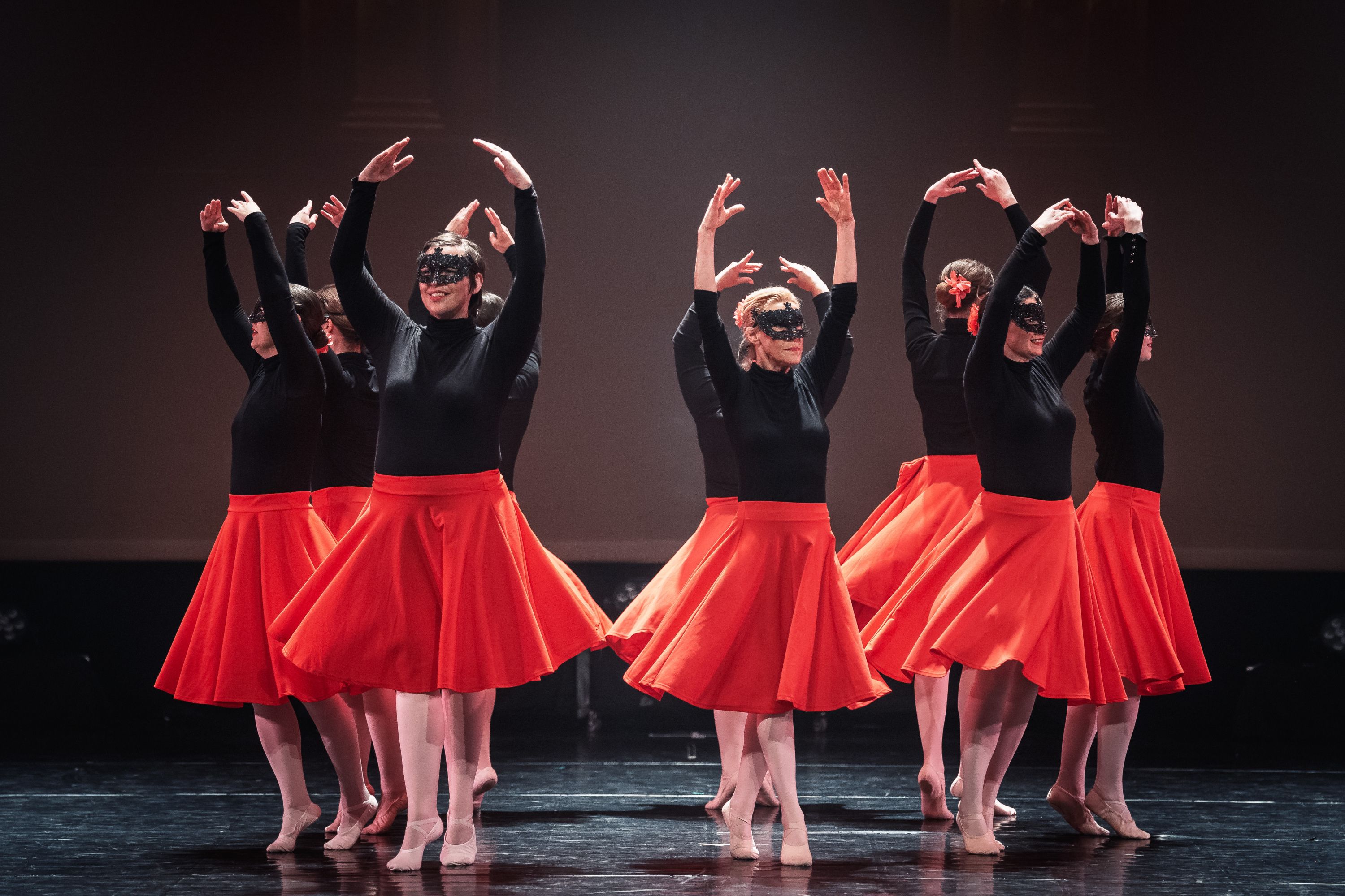 Ballet Bliss dansers van Ndigo in zwarte tops en rode rokken op het podium, armen elegant omhooggeheven.