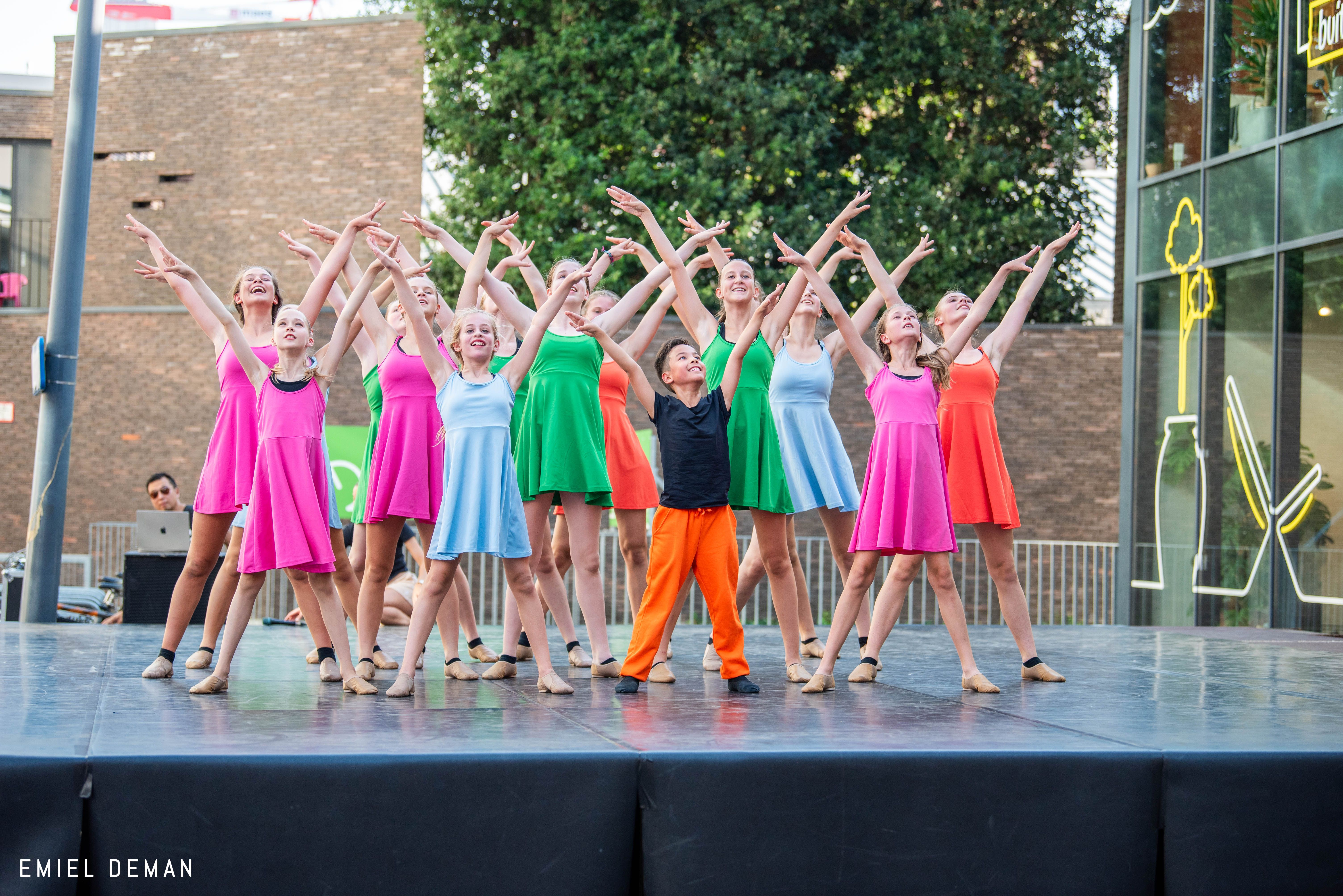 Dansers van Ndigo bewegen samen in openlucht tijdens een kleurrijk optreden dat lichamelijke ontwikkeling ondersteunt.