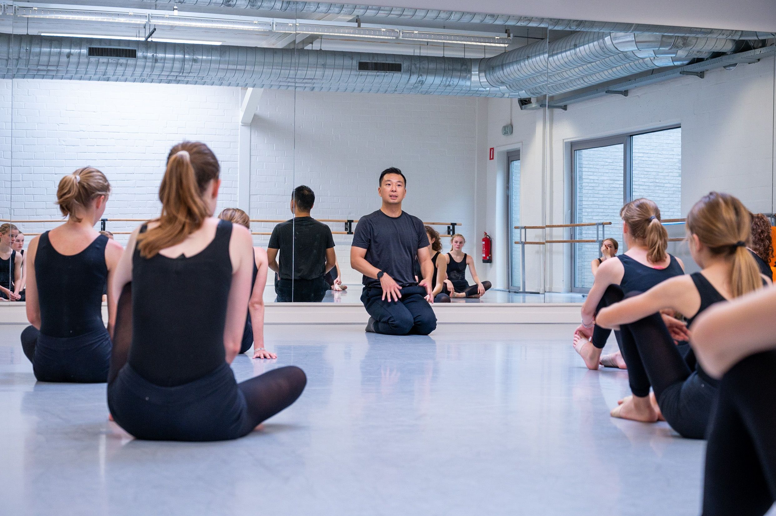 docent justin spreekt dansers toe die neerzitten op de studiovloer