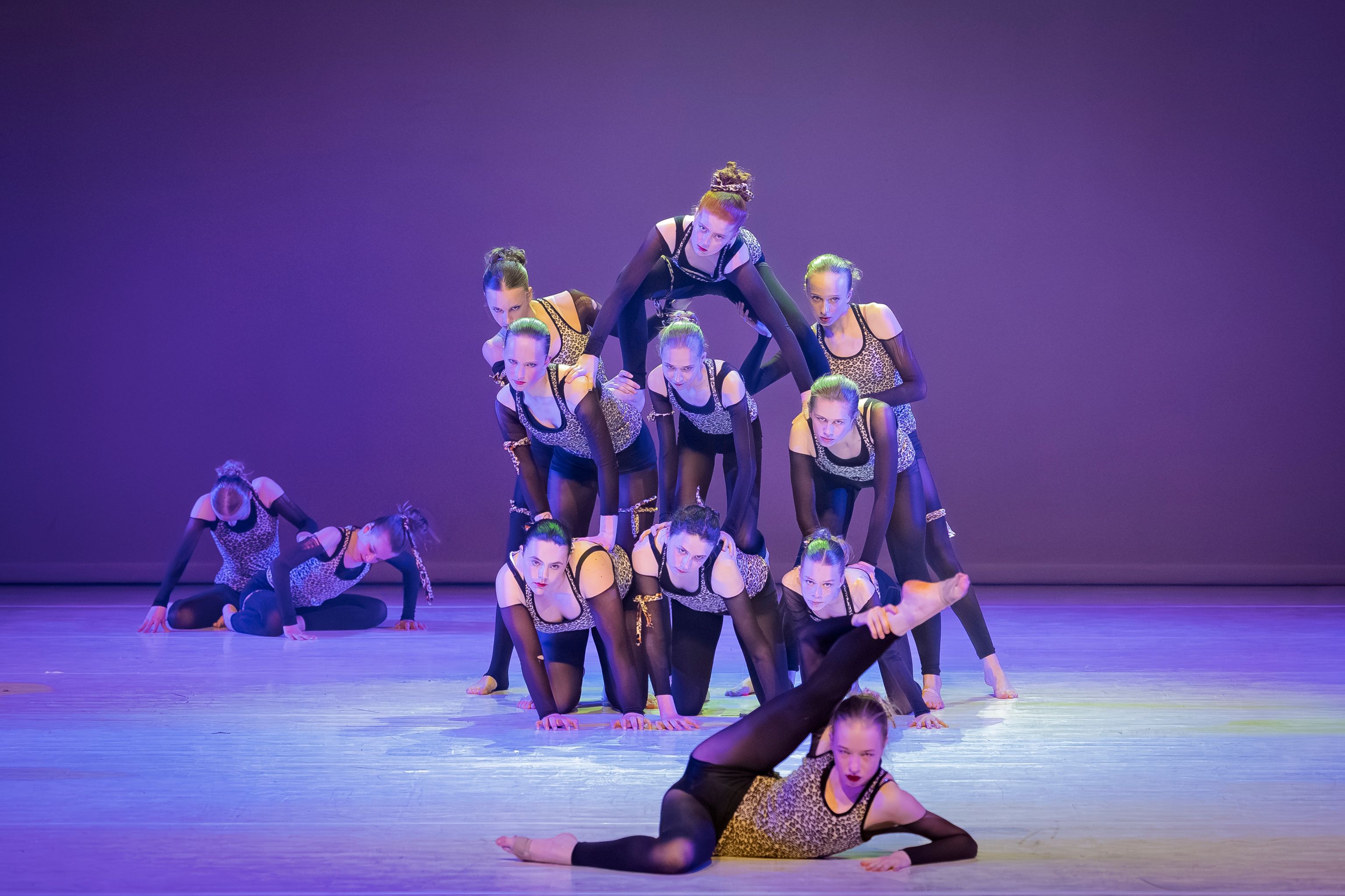Dansers van Ndigo voeren een groepschoreografie uit op het podium in Lion King-stijl, met acrobatische poses en gelaagde formaties.