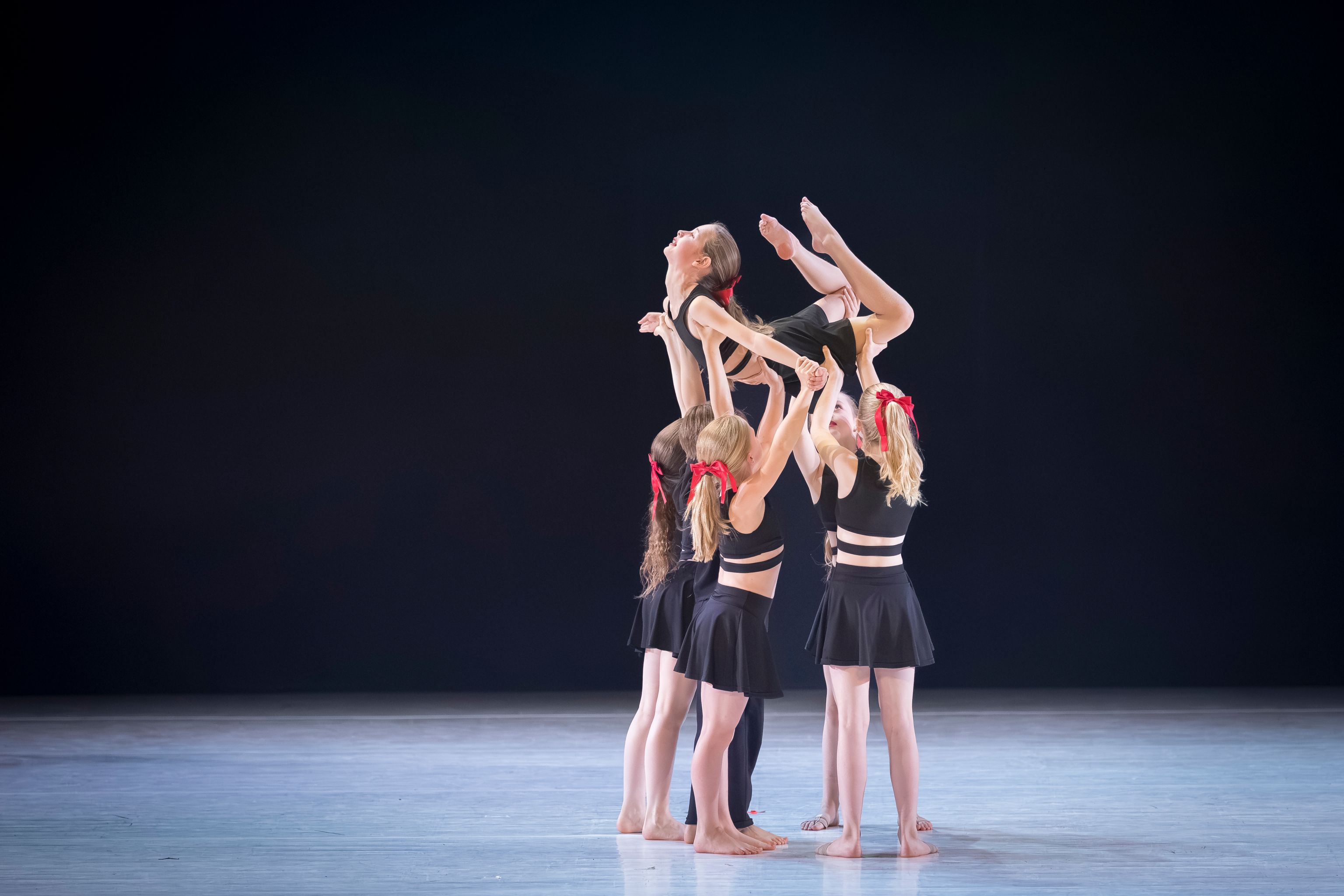 Dansers van Ndigo tonen een groepslift op het podium tijdens een optreden.
