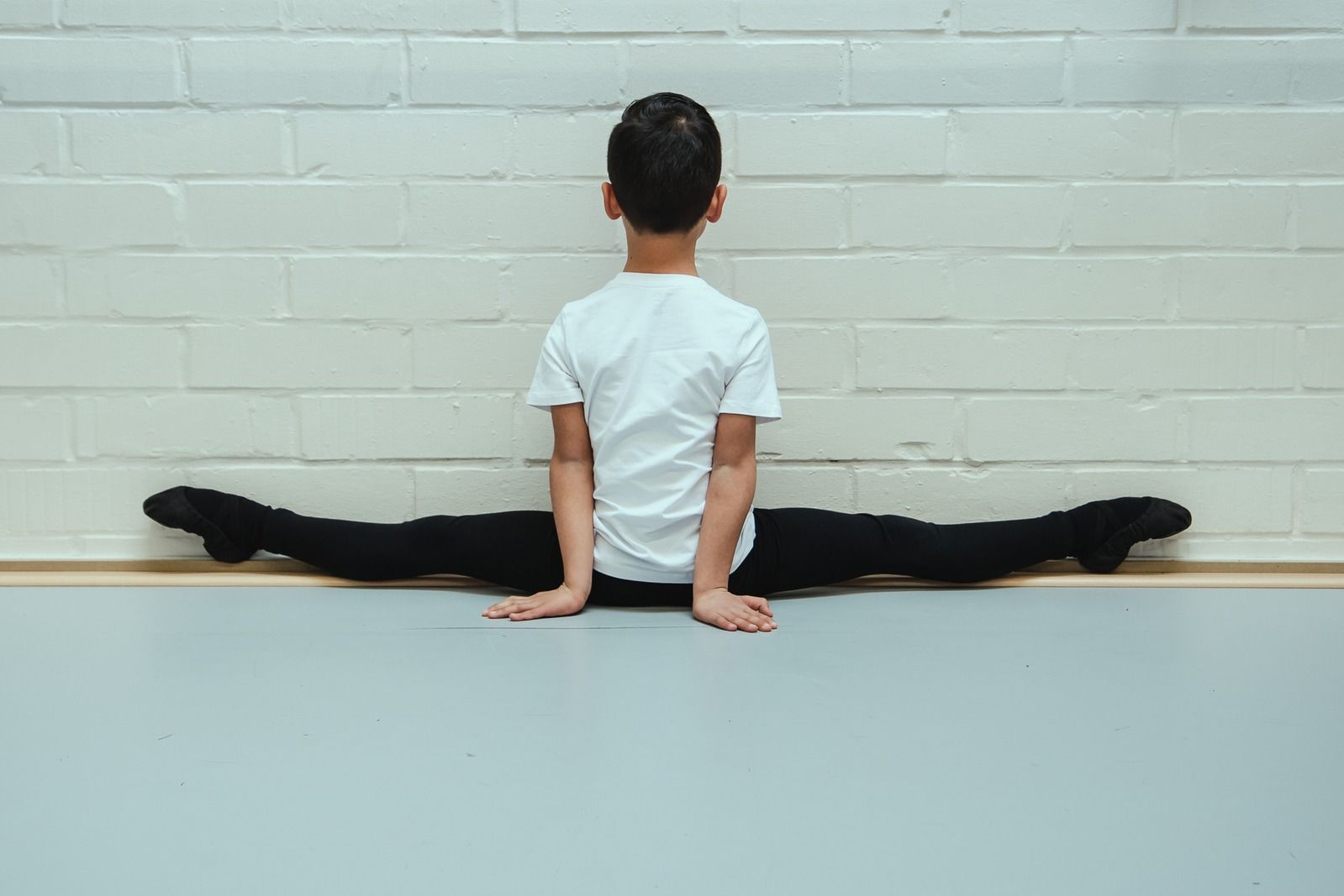 Jonge danser doet een split tijdens opwarming en stretching, als voorbereiding om soepel te bewegen en blessures te helpen voorkomen