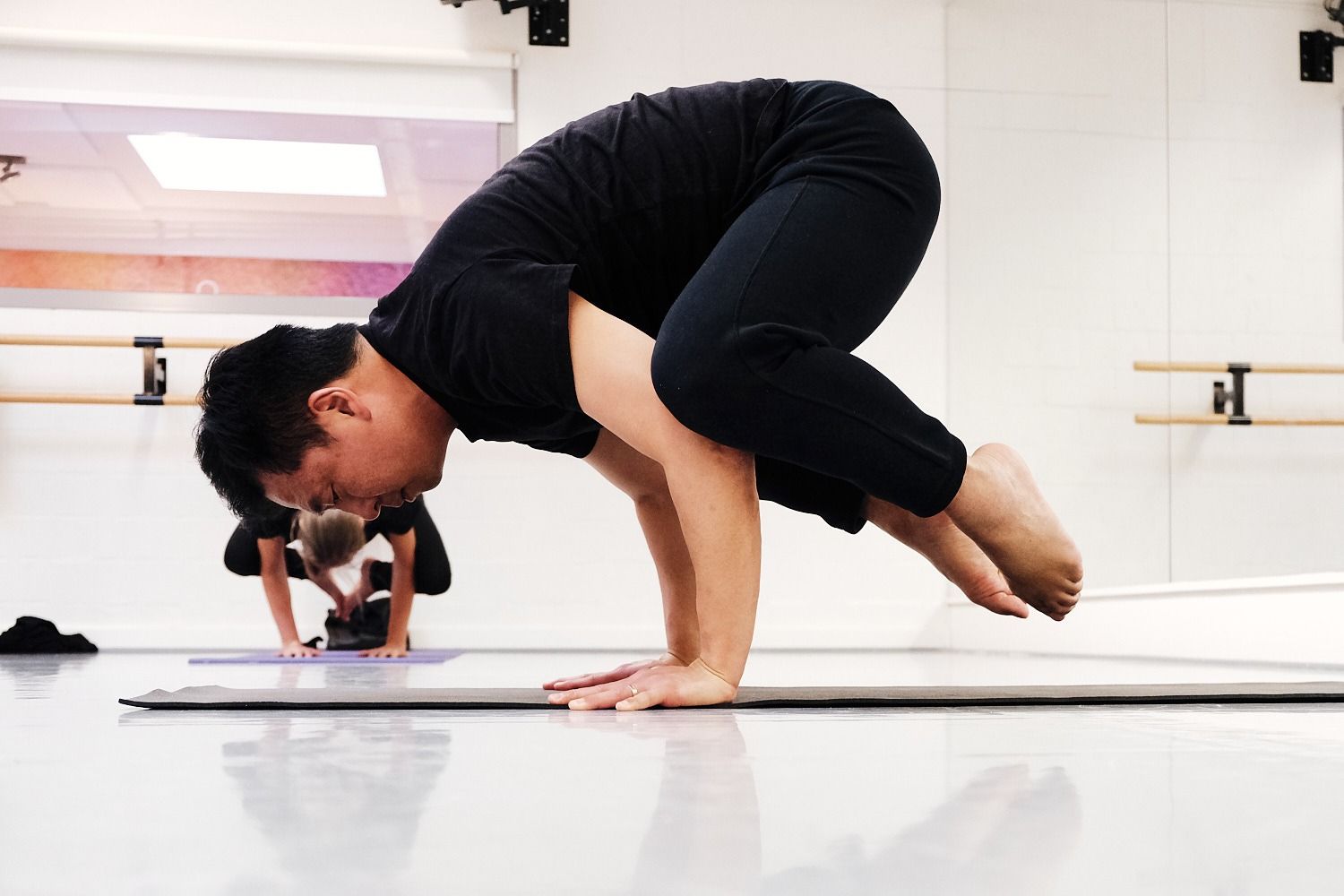 Justin begeleidt een yoga-oefening in balans op de mat, met aandacht voor houdingen op ieders niveau.